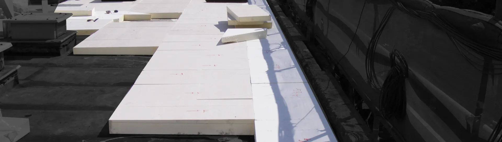 Flat roof with large white insulation panels laid out.