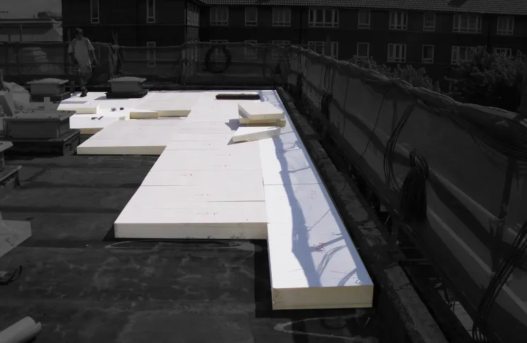 Flat roof with large white insulation panels laid out.